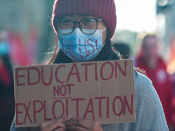 Student nurse holding a sign that says education not exploitation